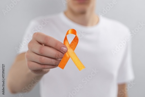 Orange Ribbon Held By A Person in A White T-Shirt.