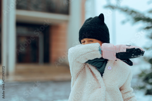 Girl With a Cold in Winter Coughs into Her Elbow. Child trying not to spread a viral disease by sneezing in elbow