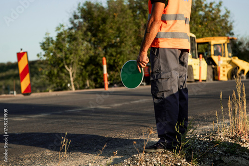 Foto Construction worker holding a stop sign on road