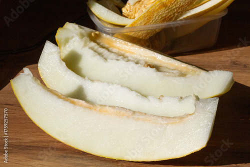 slices of sliced melon are placed on a wooden surface in sunlight