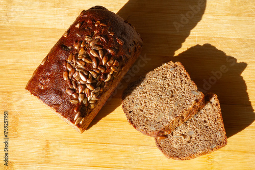 sliced rye bread with bran and seeds next to 2 slices of bread on a wooden surface, top view
