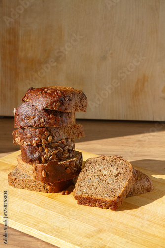 sliced bread piled up in a pyramid next to 2 pieces of bread with crust and seeds on it on a wooden surface