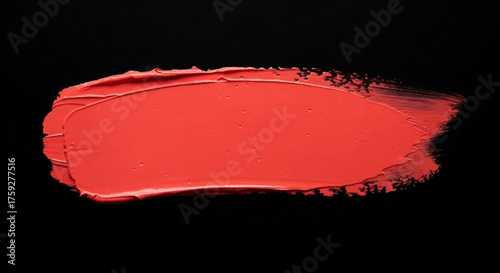 Vibrant coral lipstick texture swatch against a stark black background showing creamy application detail and smooth finish for beauty marketing and cosmetic product demonstration
