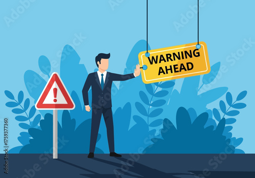 Businessman pointing at warning sign and road sign indicating danger ahead.