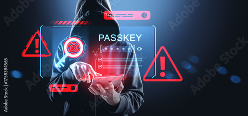 Quadro su tela Hacker in hoodie using tablet with digital passkey interface and red warning signs on futuristic cybersecurity background in blue tones