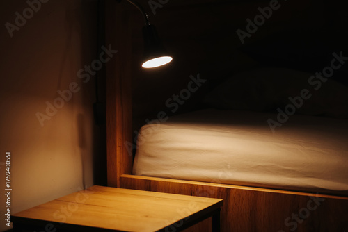 Obraz na płótnie Warm bedside lamp lighting wooden table and bed in dark cozy bedroom