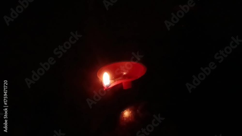 Slow-motion horizontal shot from India, a hand delicately lights a diya against a black background, capturing the essence of spiritual preparation and the vibrant warmth of Diwali festival celebration