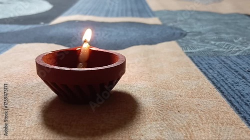 Slow-motion horizontal shot from India, a hand delicately lights a diya against a black background, capturing the essence of spiritual preparation and the vibrant warmth of Diwali festival celebration