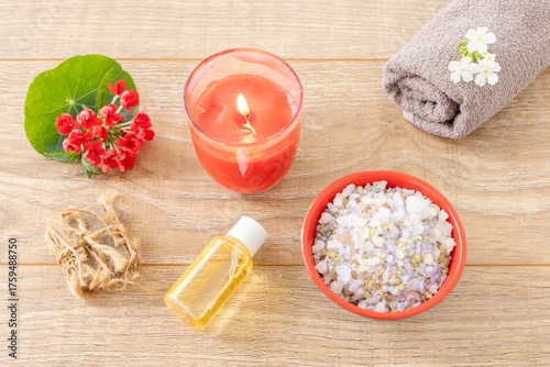 Towel with body care products and verbena flowers on the wooden background.