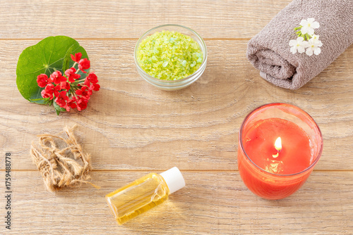 Towel with body care products and verbena flowers on the wooden background.