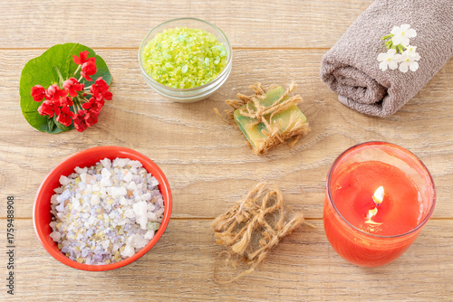 Towel with body care products and verbena flowers on the wooden background.