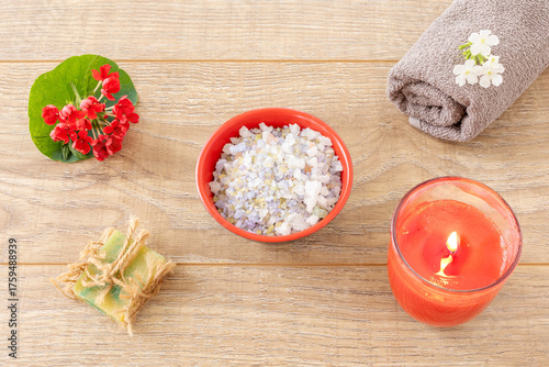 Towel with body care products and verbena flowers on the wooden background.