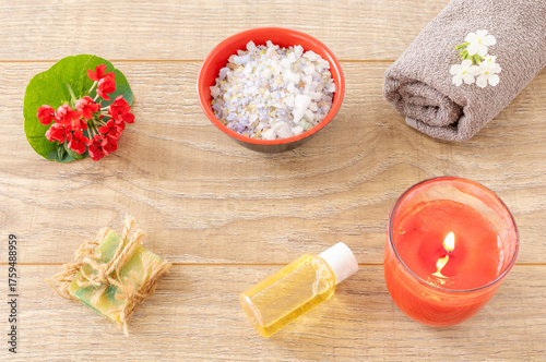 Towel with body care products and verbena flowers on the wooden background.