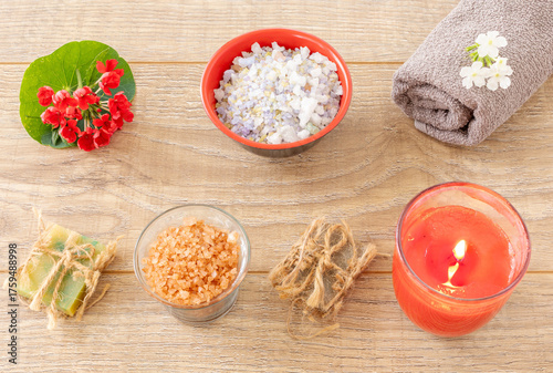 Towel with body care products and verbena flowers on the wooden background.