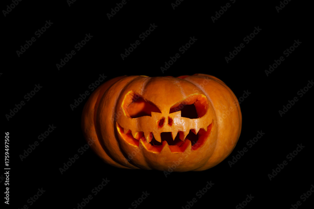 Fototapeta premium Halloween pumpkin with a scary face on a black background.