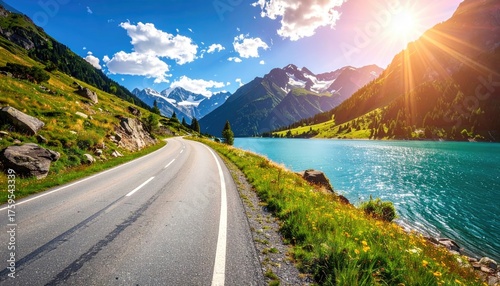 Scenic Winding Asphalt Road Alongside Turquoise Alpine Lake With Snow Capped Mountains Under Bright Sunlight And Blue Sky With Clouds