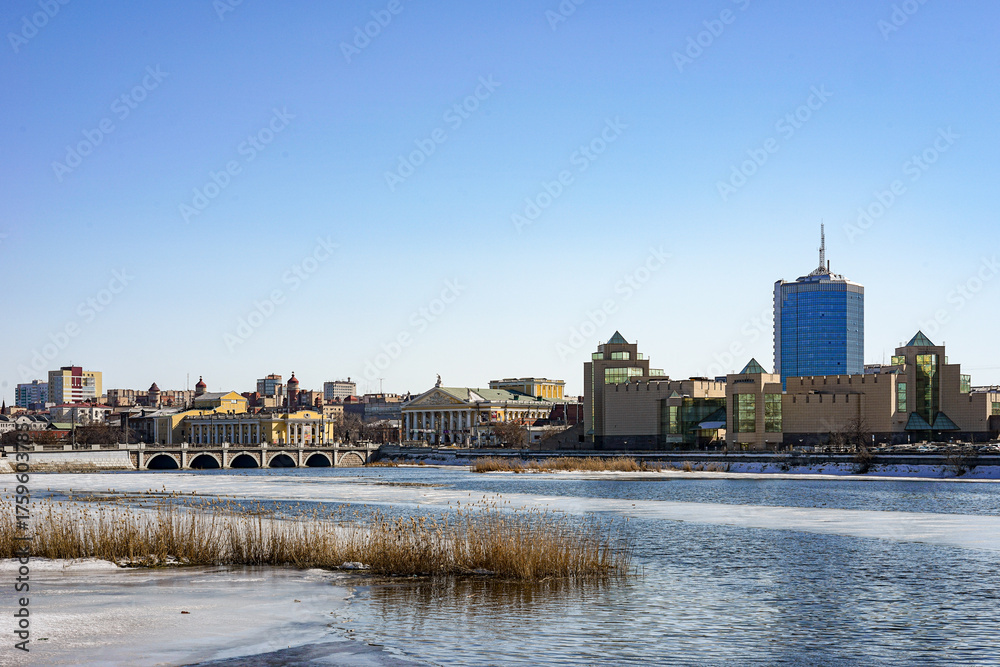 Fototapeta premium A view from the Miass River embankment in Chelyabinsk, Russia of the city's panorama, with the blue Chelyabinsk City high-rise building visible in the background The weather frosty sky light and blue