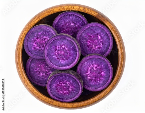 Top view of sliced purple sweet potatoes in a wooden bowl, showcasing their vibrant color and texture.