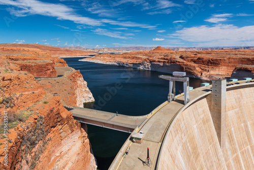 Aerial view of the Glen Canyon Dam on the Colorado River in Arizona, USA. Impressive hydroelectric structure surrounded by red sandstone cliffs and desert landscape, forming Lake Powell.