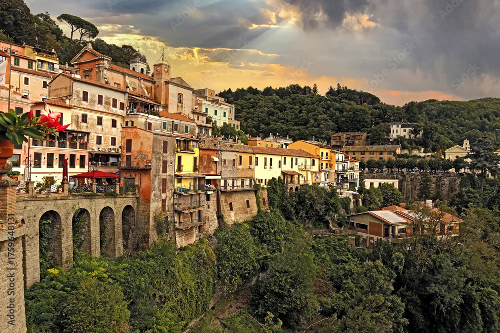 Fototapeta premium Casette e Archi del Borgo di Nemi sulla Collina Sotto un Cielo Drammatico, Nemi, Borgo storico