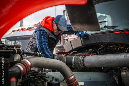 Caucasian Mechanic Checks Engine in Heavy Truck During Overcast Day