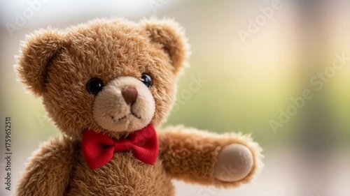 Cute teddy bear waving hello with a red bow tie, soft focus background of a warm, inviting room
