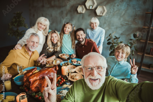 Joyful big family Thanksgiving dinner with grandparents grandchildren friends and loved ones gathered around a festive table and sharing gratitude