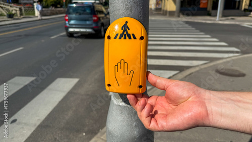 Fotografía A hand poised on a vivid yellow crosswalk button, heralding pedestrian rights, I