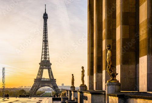Sunrise on the Eiffel Tower and the golden statues of the Trocadero esplanade along the Chaillot palace in Paris, France.