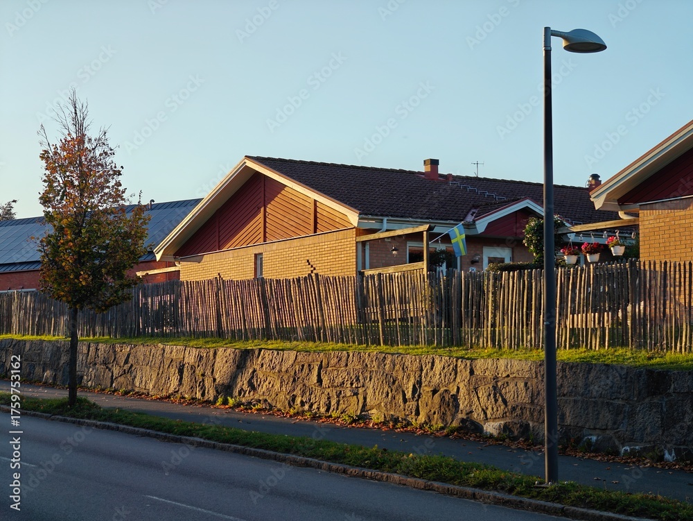 Obraz premium Road along beautiful and cozy residential houses in Sweden during golden hour with a warm autumn atmosphere