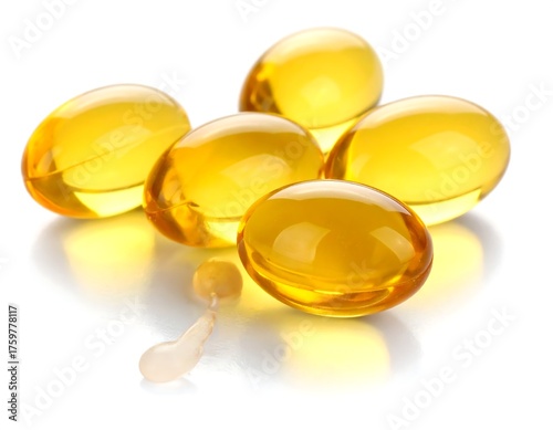 Close-up of soft, translucent, yellow capsules with one burst open, on a white surface