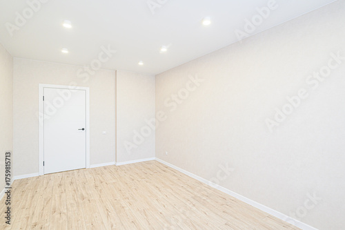 Bright, empty room with wood-like flooring, white walls, a white door, and recessed ceiling lights