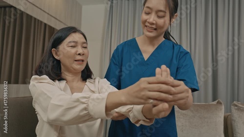 asian female caregiver assisting senior woman with physical therapy exercise at home during rehabilitation process to improve mobility strength and overall health care support in daily life