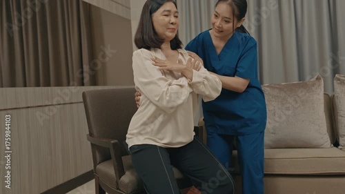 asian female caregiver assisting senior woman with physical therapy exercise at home during rehabilitation process to improve mobility strength and overall health care support in daily life