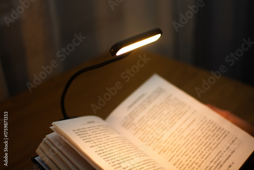 A convenient clip-on reading lamp with color options, placed over a book on the table for reading