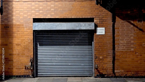 Urban brick wall with a silver metal roller shutter door at night, great for grunge, security, storage, and city backgrounds