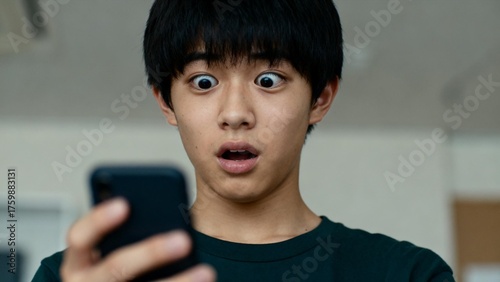 スマートフォンを見ながら驚く男の子