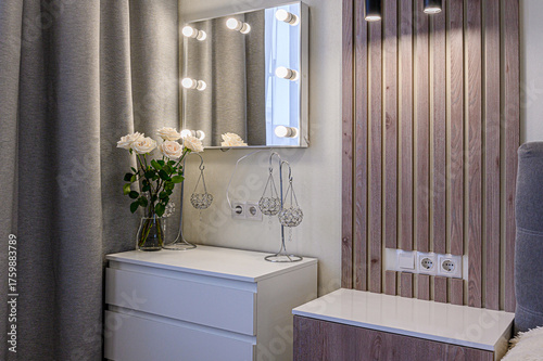 Cozy bedroom corner with a vanity mirror, white dresser, roses, and wood-paneled accent wall. Soft, elegant, and inviting