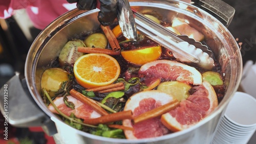 Fotografie Mulled wine simmering in pot with cinnamon sticks, orange and grapefruit slices