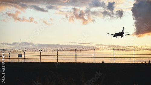 Airplane landing during sunset, silhouette of aircraft in beautiful evening sky