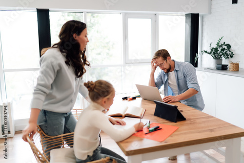 Photography Mom, dad and daughter experience visible stress and mental load of remote work and learning, visualizing daily challenges of digital coexistence within one multifunctional household