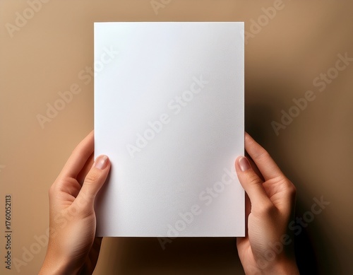 Woman's Hands Holding a Blank White Cardboard, Mockup Template for Design Presentation, Invitation, Letter, or Message on a Neutral Beige Background