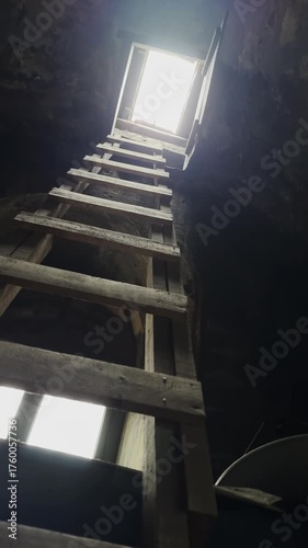 Climbing a ladder to the roof with light from the sky vertical video