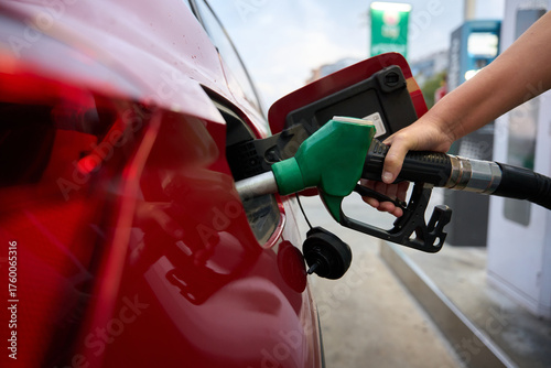 Hand refueling red car with gasoline fuel nozzle oil and gas price crisis