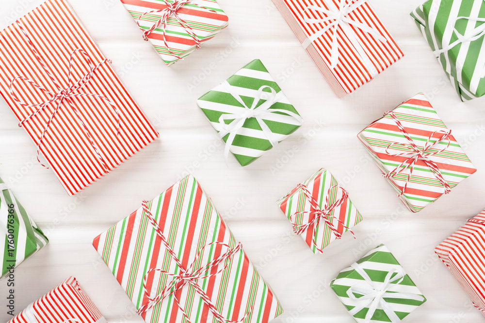 Obraz premium Many striped Christmas gift boxes on wooden background, top view