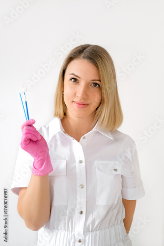 A female doctor in pink gloves holds brushes in her hands to take a smear analysis from the cervical canal for cytological examination.