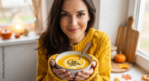 Woman Holding Delicious Creamy Pumpkin Soup With Autumn Decorations