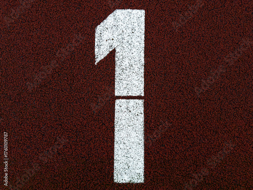 White number one painted on red running track surface, close-up of athletic field marking with textured background, symbolizing start, leadership, competition and first place