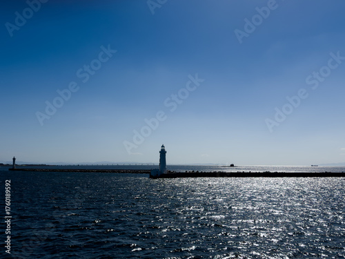 A submarine on the surface of the ocean with sparkling seas and a lighthouse in the foreground
