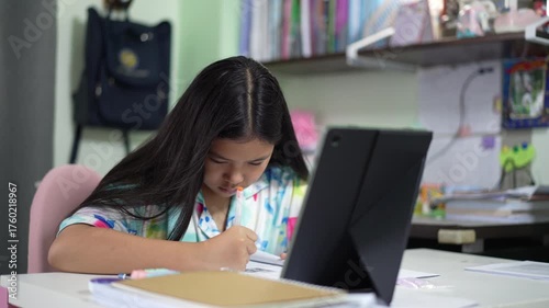 asian child student fun study online and writing on book or young kid girl smile learn from home with computer tablet by video call and write or people studying by homeschool and back to school
